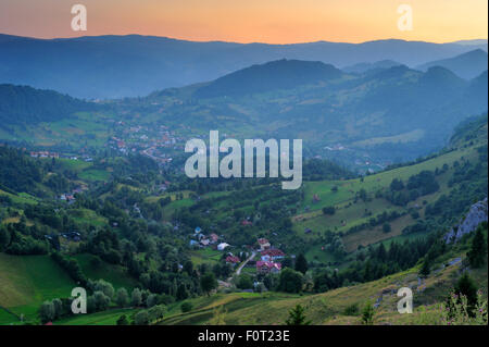 Vue d'une vallée et village dans le sud du massif des Carpates au coucher du soleil, la Roumanie, juillet 2011 Banque D'Images