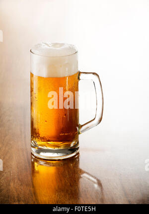 Verre de bière froide sur une table en bois. Banque D'Images