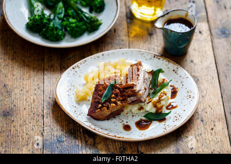 Flan de porc avec grésillement, purée de pommes, de la compote de pomme et de feuilles de sauge frites Banque D'Images