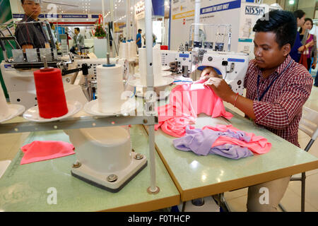 Phnom Penh, Cambodge. Août 21, 2015. Un homme utilise une machine pour l'industrie textile et du vêtement dans une exposition à Phnom Penh, Cambodge, 21 août 2015. La 5ème Conférence internationale de l'habillement et l'équipement industriel exposition a lieu ici le vendredi. Credit : Phearum/Xinhua/Alamy Live News Banque D'Images