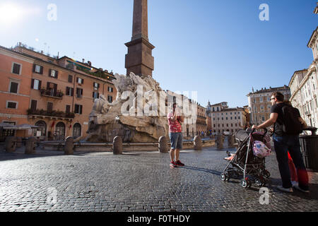 Rome, Italie, 21 août 2015. Météo Italienne : le lever du soleil dans le centre de Rome. Au cours de l'été, les bureaux du centre historique de Rome sont vidés et il semble que les rues désertes. Dans cette photo les touristes de prendre des photos en face de la fontaine par Gian Lorenzo Bernini Banque D'Images