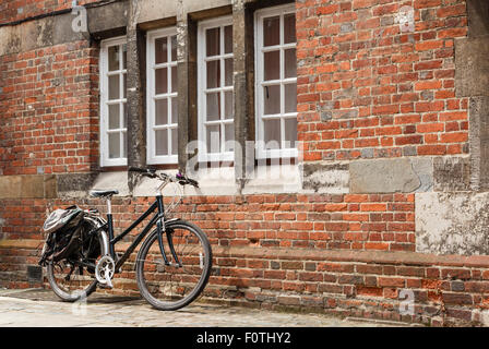 Vélo rétro contre le mur de brique d'un vieux bâtiment avec personne. Banque D'Images