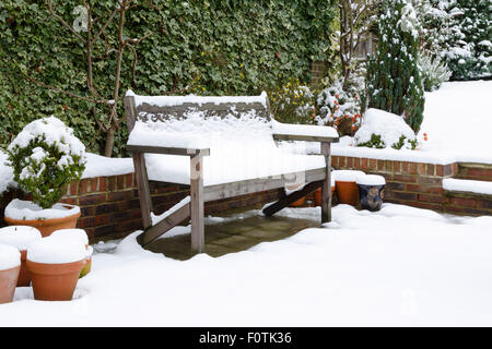 Banc de jardin couvert de neige sur un patio en hiver Banque D'Images