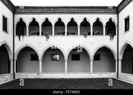 Cloître rectangulaire avec des arcs gothiques et des colonnes de marbre. Au premier étage une belle loggia avec arches gothiques trèfle. Banque D'Images