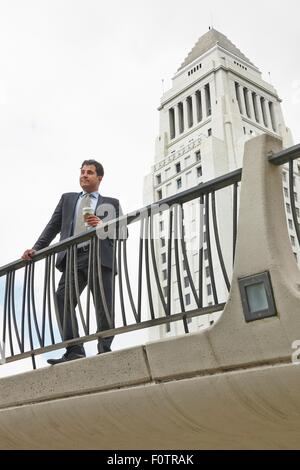 Business man standing on walkway holding coffee, l'Hôtel de ville de Los Angeles, Californie, USA Banque D'Images