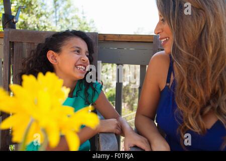 Mère et fille sur le banc de jardin avec fleurs jaune Banque D'Images