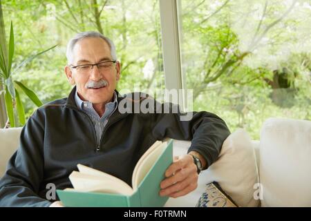 Senior man at home, reading book Banque D'Images