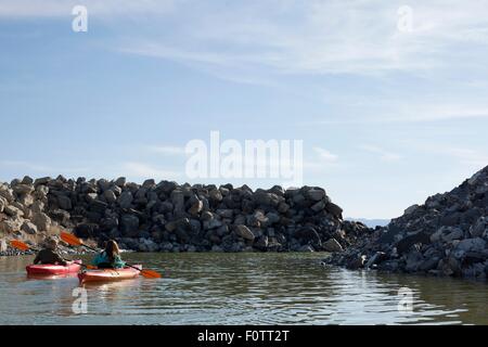 Vue arrière des kayakistes assis sur l'eau dans les roches, les kayaks face à Great Salt Lake, Utah, États-Unis Banque D'Images