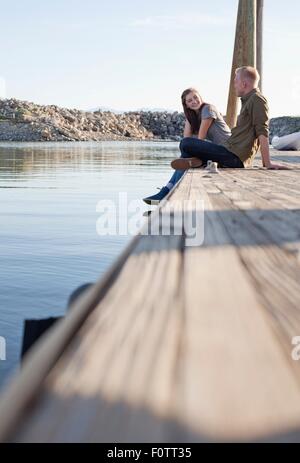 Side view of young couple sitting on wooden pier parler, Grand Lac Salé, Utah, USA Banque D'Images