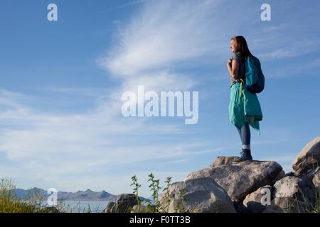 Vue arrière du jeune femme portant sur l'article sac à dos rocks à la suite, Grand Lac Salé, Utah, USA Banque D'Images