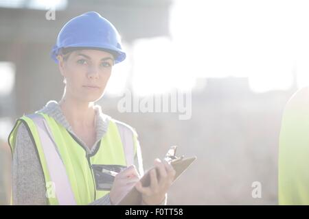 Portrait de femme-géomètre avec presse-papiers on construction site Banque D'Images