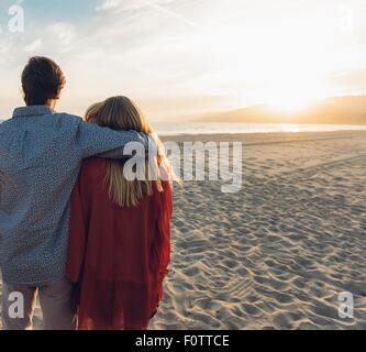 Jeune couple standing on beach, s'étreindre, vue arrière Banque D'Images
