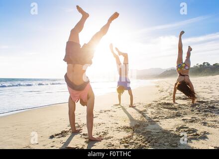 Groupe d'amis faisant handstands on beach Banque D'Images