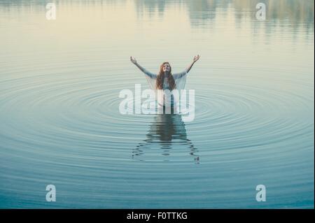 Jeune femme debout au milieu du lac ondulations avec bras ouverts Banque D'Images