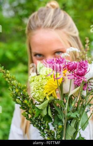 Portrait de jeune femme derrière bouquet de fleurs Banque D'Images
