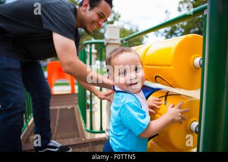 Jeune homme jouant avec tout-petit frère à l'équipement de jeu Banque D'Images