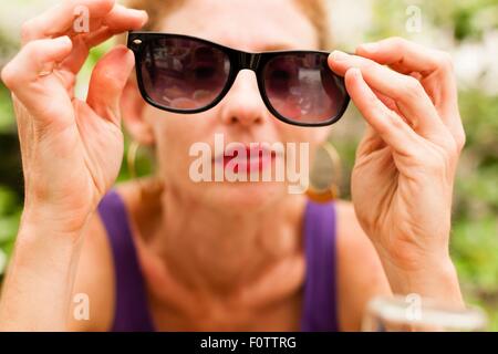 Mid adult woman holding lunettes devant ses yeux Banque D'Images