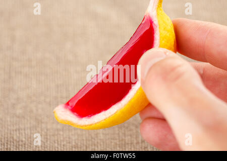 Homme main tenant une gelée de fraises tequila citron (jello shot). Selective focus on un shooter Banque D'Images