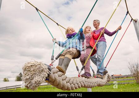 Grand-mère et ses petits-enfants jouant sur le pont de corde, low angle view Banque D'Images