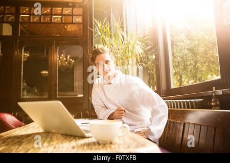 Jeune chef assis au travail looking at camera Banque D'Images