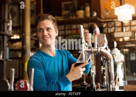 Jeune homme travaillant dans la maison, servant des boissons Banque D'Images