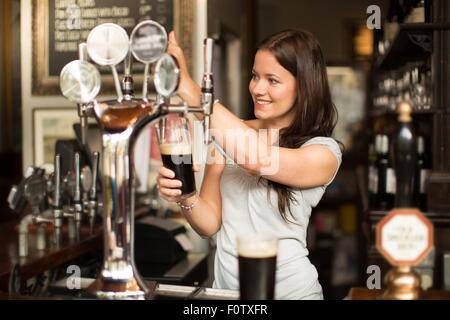 Mid adult woman travaillant dans les chambre, servant des boissons Banque D'Images