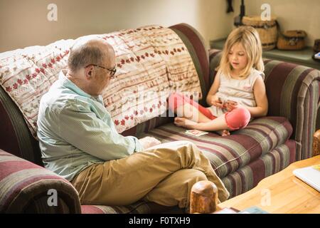 Grand-père et petite-fille de cartes à jouer sur canapé Banque D'Images