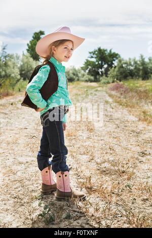 Girl wearing cowboy hat et bottes sur le chemin Banque D'Images