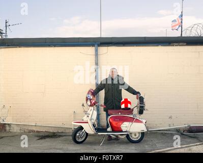 Portrait de mâle mature mod avec un cyclomoteur en face de wall Banque D'Images