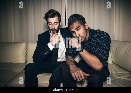 Deux jeunes hommes assis sur canapé Banque D'Images