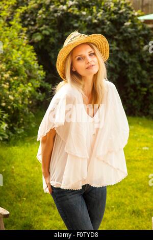 Portrait of mid adult woman avec de longs cheveux blonds portant chapeau de jardin Banque D'Images