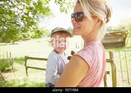 Portrait of mature woman carrying toddler son in field Banque D'Images