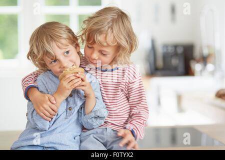 Jeune garçon muffin manger alors que son frère regarde sur Banque D'Images