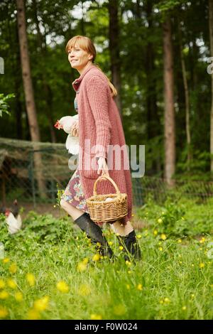 Femme portant des oeufs de poule et panier Banque D'Images