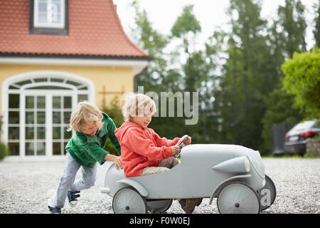 Deux garçons jouant avec vintage toy voiture en face de la maison Banque D'Images