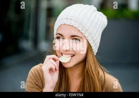 Adolescentes dans la rue en plein air eating chips Banque D'Images