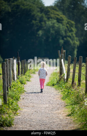 Petite fille menant la marche en jouant sur la voie avec un bâton qu'elle a trouvés. Banque D'Images