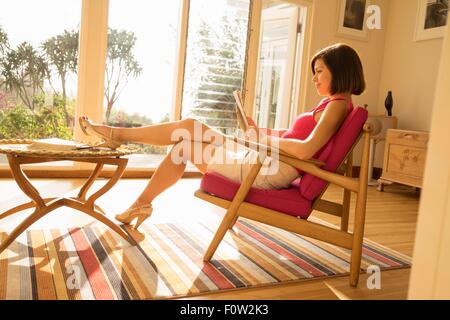 Businesswoman reading paperwork in living room Banque D'Images