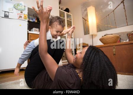 Mid adult woman lying on rug jouer avec bébé fille Banque D'Images