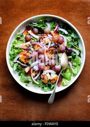 Bol de salade mixte avec l'oignon rouge et le raisin noir Banque D'Images