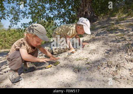 Deux jeunes garçons, Playing with toy cars on sand Banque D'Images