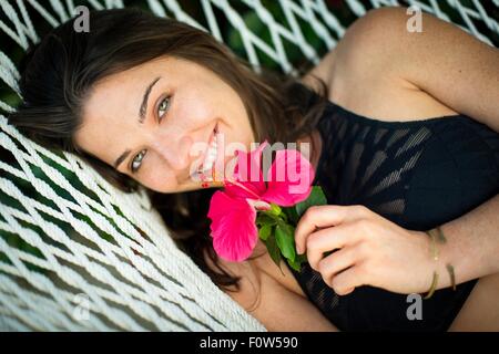 Portrait de jeune femme sur hamac avec fleur rose Banque D'Images