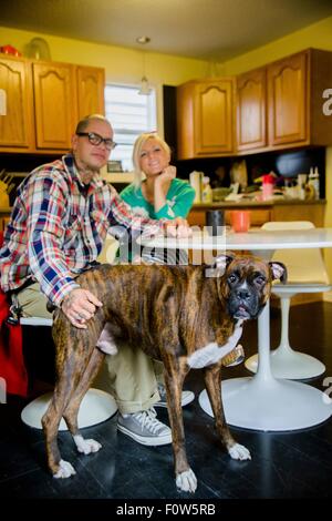 Couple assis à une table à manger avec chien boxer Banque D'Images