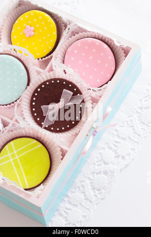 Les cookies de sucre coloré. Focus sélectif. La boîte en bois est peint en bleu clair et décoré avec un ruban de satin rose pâle Banque D'Images