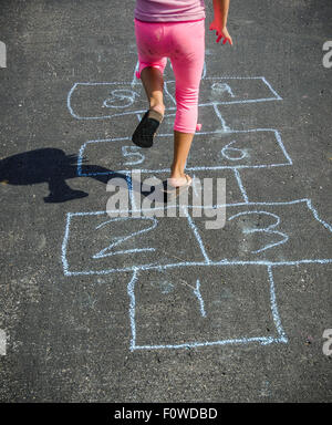 Jeune fille à l'autre lors d'un jeu à l'extérieur sur une chaude journée ensoleillée portant des pantalons et des sandales Rose Banque D'Images