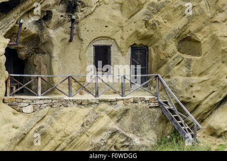 Unique habitation taillée dans la roche avec terrasse en bois dans un paysage montagneux présente des techniques architecturales anciennes Banque D'Images