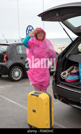 Vacancier femelle à une station balnéaire humide de déballer sa voiture. UK Banque D'Images