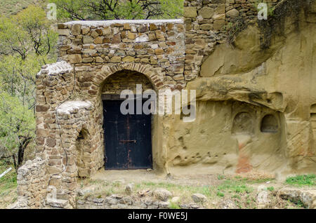 Unique habitation taillée dans la roche avec terrasse en bois dans un paysage montagneux présente des techniques architecturales anciennes Banque D'Images