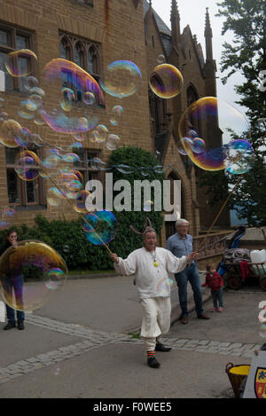 Un artiste de rue souffle des bulles de savon géantes pour amuser les enfants au Château de Hohenzollern, Bade-Wurtemberg, Allemagne Banque D'Images