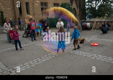 Un artiste de rue souffle des bulles de savon géantes pour amuser les enfants au Château de Hohenzollern, Bade-Wurtemberg, Allemagne Banque D'Images